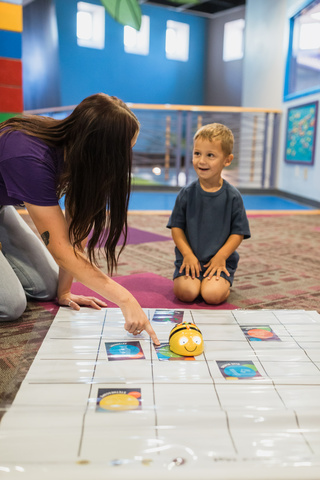 Museum employee engaging with student using Bee Bots