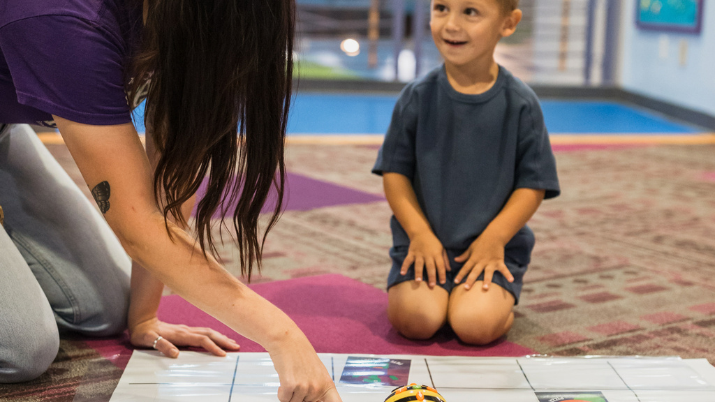 Museum employee engaging with student using Bee Bots