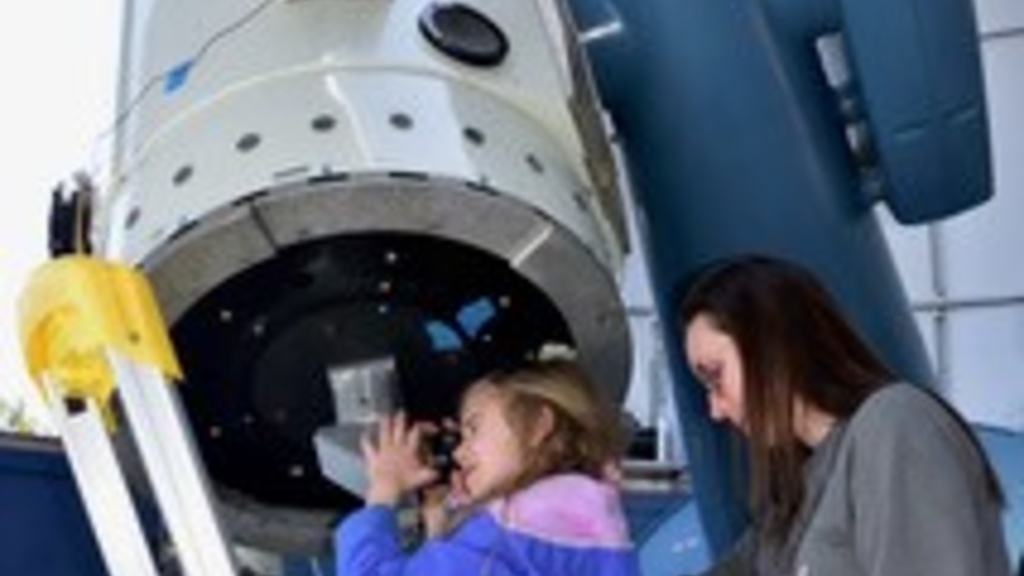 Kid looks through a large telescope