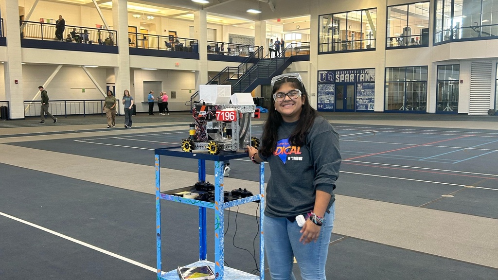 Person posing next to robot at robotics competition