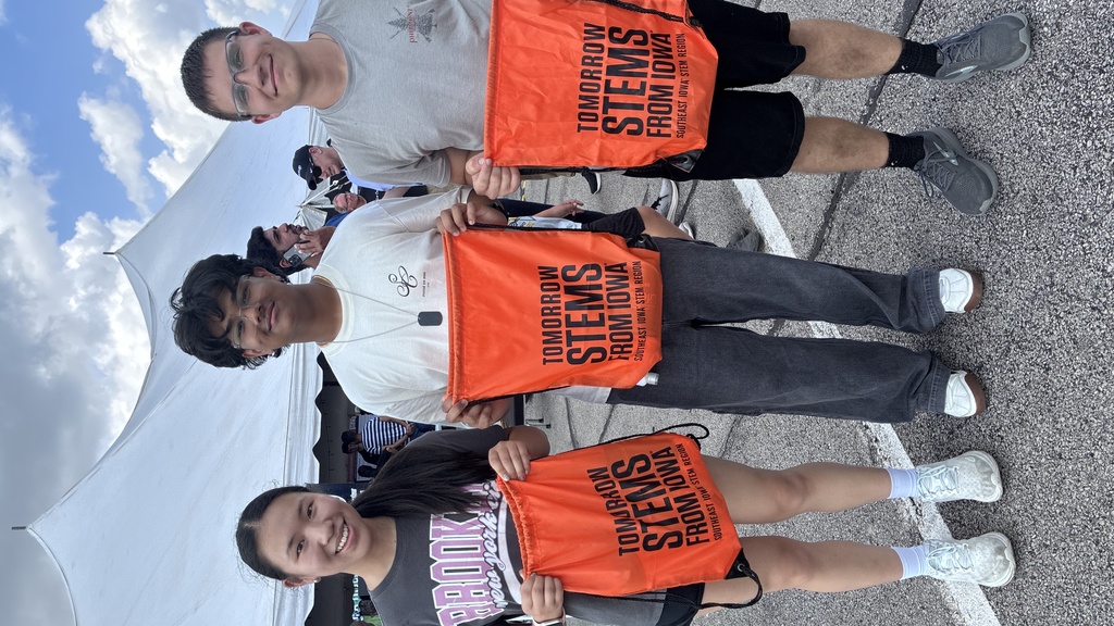 Three people holding orange backpacks