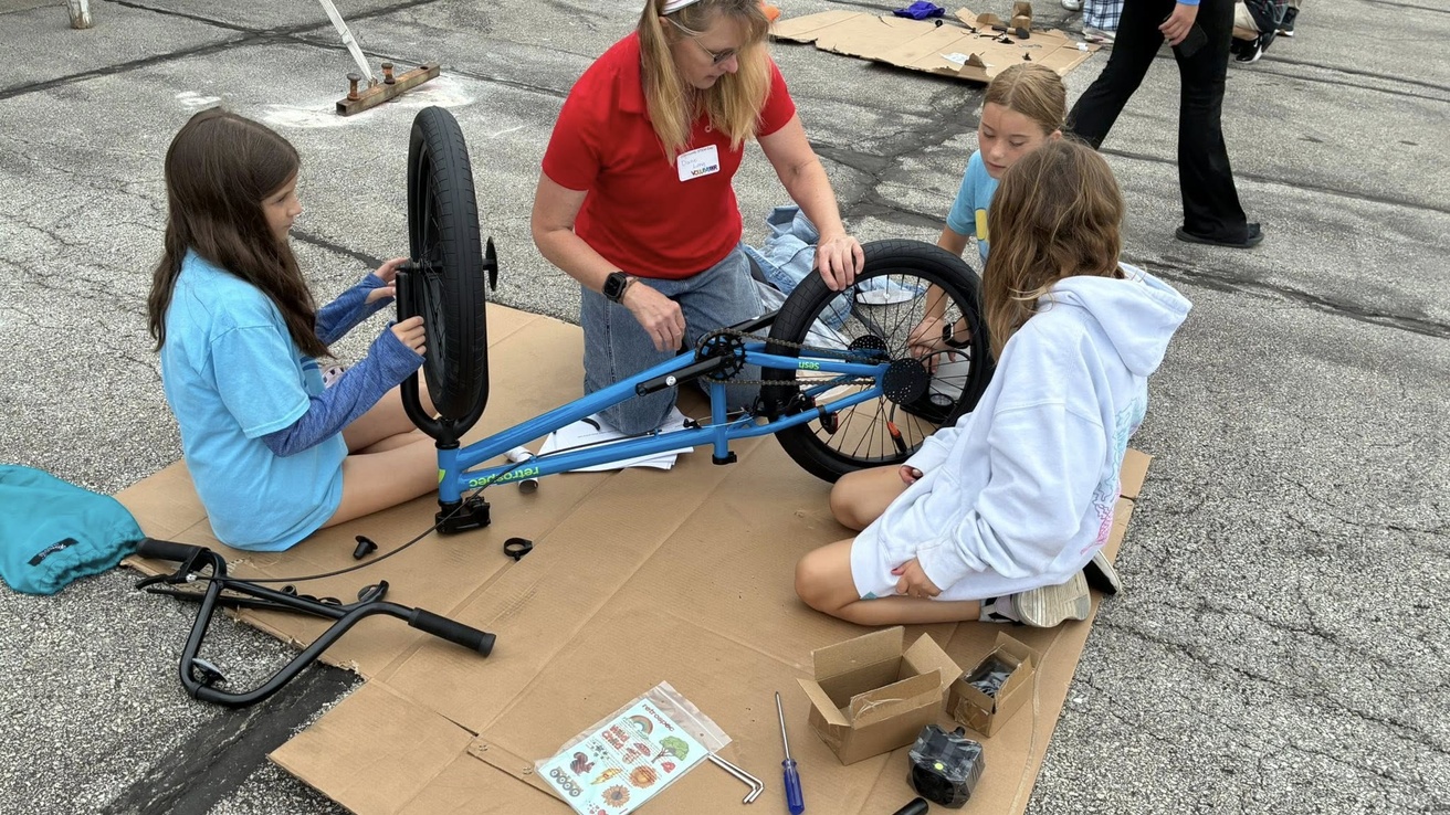 Three kids and an adult building a bike